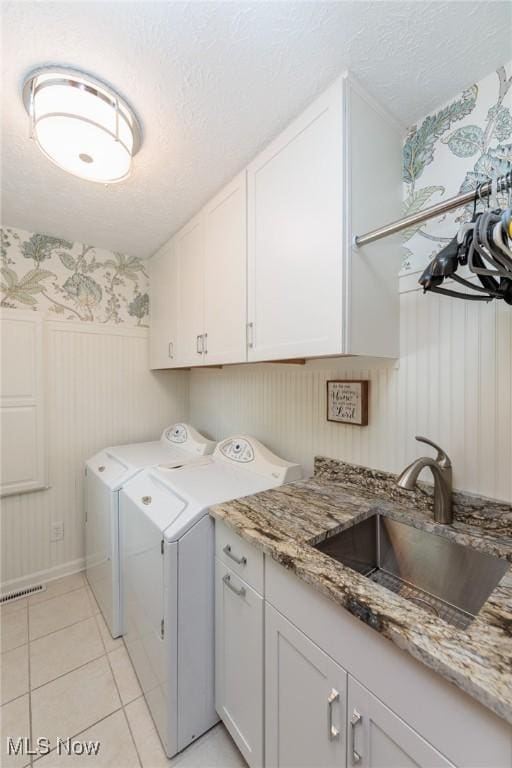 6252 Pebblebrook Ln, North Olmsted, OH 44070 - washroom featuring cabinet space, washer and clothes dryer, wallpapered walls, a textured ceiling, and light tile patterned flooring