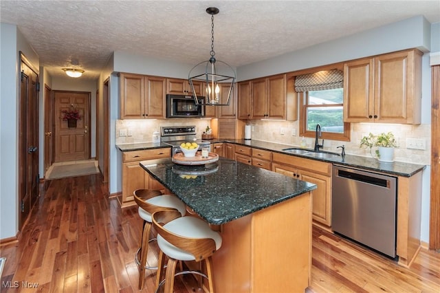 6252 Pebblebrook Ln, North Olmsted, OH 44070 - kitchen featuring stainless steel appliances, wood-type flooring, a kitchen breakfast bar, a kitchen island, and a textured ceiling