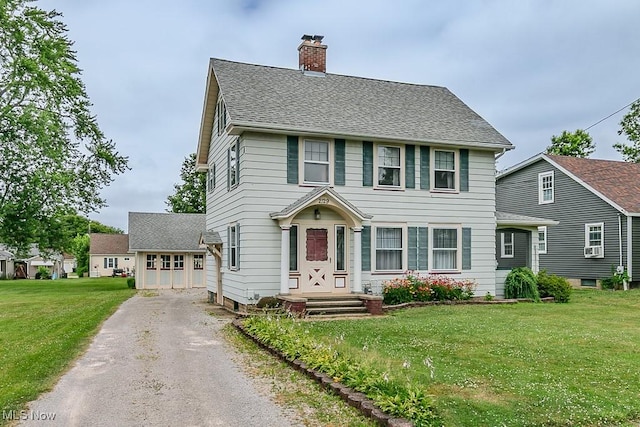 2129 E 41st St, Ashtabula, OH 44004 - colonial house featuring a chimney, driveway, a front yard, a garage, and a shingled roof