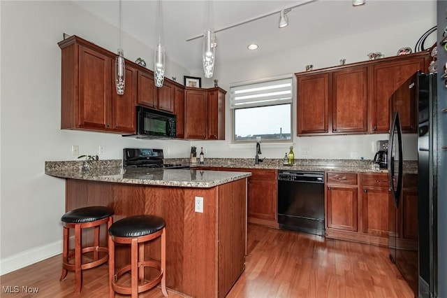 12591 Larchmere Blvd Unit W-6, Cleveland, OH 44120 - kitchen featuring black appliances, a peninsula, stone countertops, light wood-style floors, and a kitchen bar