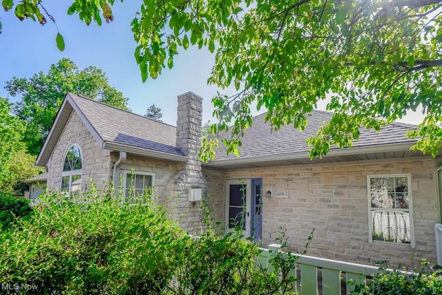 4039 Tannybrooke Ln NW Unit C, Canton, OH 44718 - rear view of house featuring stone siding, a shingled roof, and a chimney