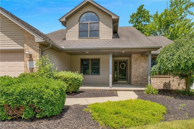 230 Clingan Rd, Struthers, OH 44471 - view of front of property featuring a porch, brick siding, roof with shingles, and an attached garage