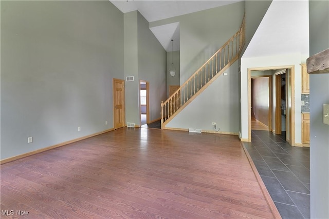 230 Clingan Rd, Struthers, OH 44471 - unfurnished living room featuring high vaulted ceiling, stairway, and dark wood-style floors