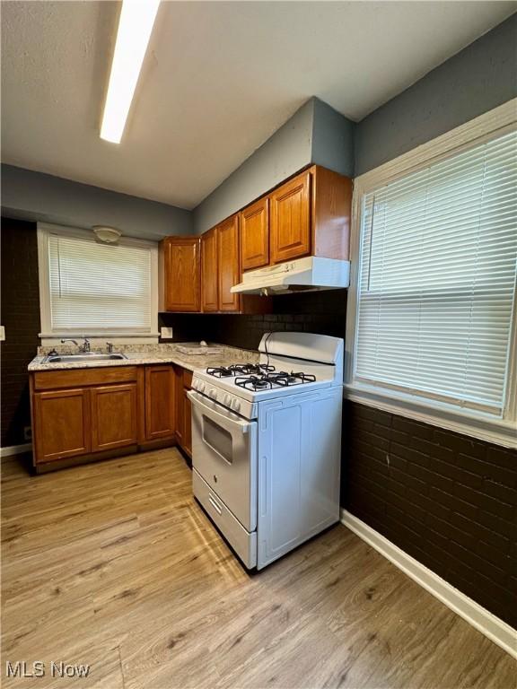 1372 Frederick Blvd, Akron, OH 44320 - kitchen with gas range gas stove, under cabinet range hood, light wood finished floors, and brown cabinetry