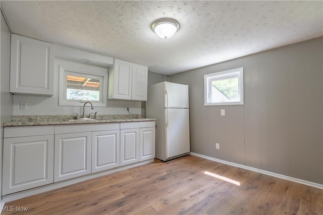 312 28th St SW, Canton, OH 44706 - kitchen featuring freestanding refrigerator, light wood finished floors, white cabinetry, a textured ceiling, and light stone counters