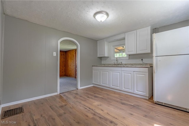 312 28th St SW, Canton, OH 44706 - kitchen featuring freestanding refrigerator, arched walkways, light wood-type flooring, white cabinetry, and a textured ceiling