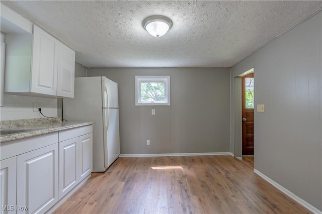 312 28th St SW, Canton, OH 44706 - kitchen with light wood-style floors, freestanding refrigerator, white cabinetry, and a textured ceiling
