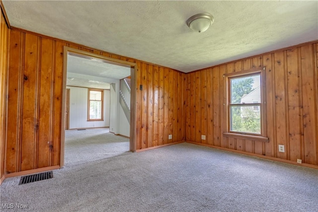 312 28th St SW, Canton, OH 44706 - carpeted spare room with a textured ceiling, healthy amount of natural light, stairway, and wood walls