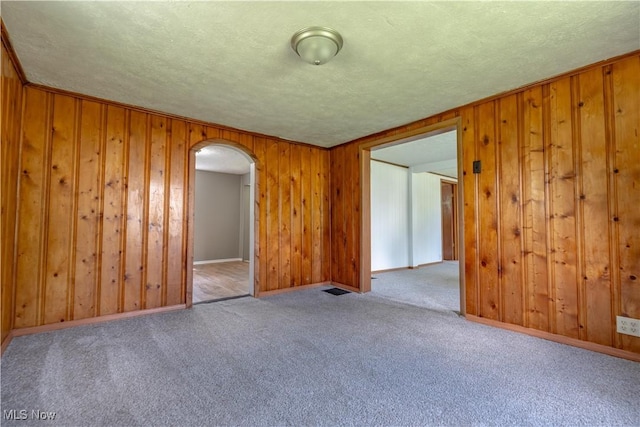 312 28th St SW, Canton, OH 44706 - carpeted empty room with arched walkways, wood walls, and a textured ceiling