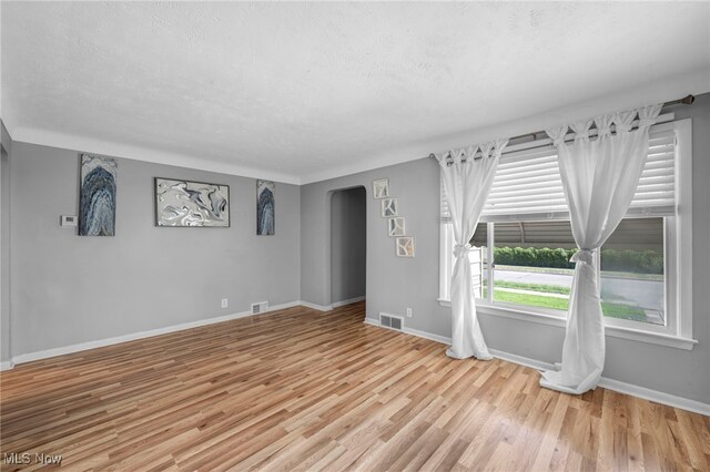 24850 Shoreview Ave, Euclid, OH 44123 - unfurnished room with arched walkways, wood finished floors, and a textured ceiling