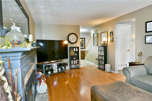 252 Greenbriar Dr, Cortland, OH 44410 - living room with stairway, hardwood / wood-style floors, a brick fireplace, and a textured ceiling