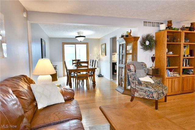 252 Greenbriar Dr, Cortland, OH 44410 - living room with a textured ceiling, wood finished floors, and wainscoting