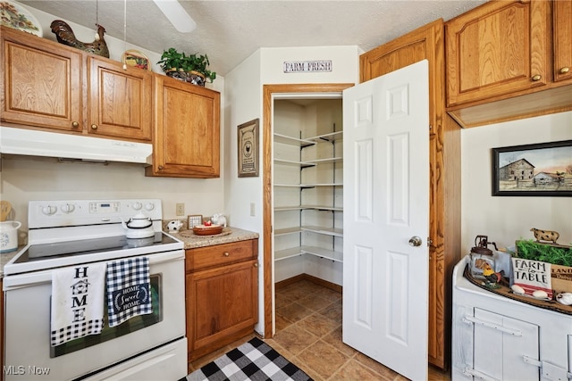 3823 Kyle Rd, Dorset, OH 44032 - kitchen with white range with electric stovetop, under cabinet range hood, light countertops, light tile patterned flooring, and brown cabinets