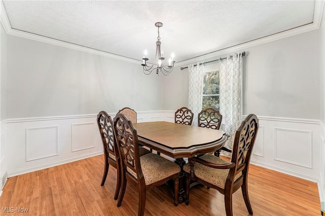 300 Chatham Dr, Aurora, OH 44202 - dining area with wainscoting, a chandelier, crown molding, light wood finished floors, and a decorative wall