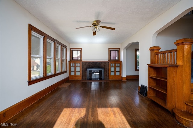 289-2891/2 E Baird Ave, Barberton, OH 44203 - unfurnished living room with wood finished floors, ceiling fan, arched walkways, a brick fireplace, and a textured ceiling