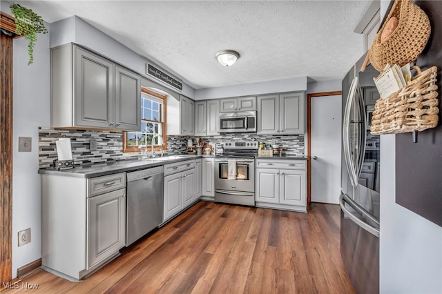 9827 Akron Rd, Rittman, OH 44270 - kitchen with stainless steel appliances, gray cabinets, dark wood finished floors, tasteful backsplash, and a textured ceiling
