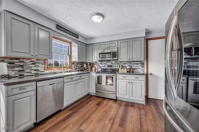 9827 Akron Rd, Rittman, OH 44270 - kitchen featuring appliances with stainless steel finishes, gray cabinets, a textured ceiling, decorative backsplash, and dark wood-type flooring