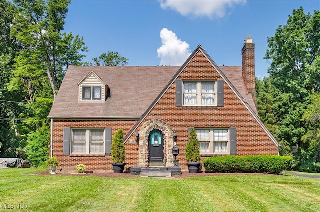 6100 Glenwood Ave, Boardman, OH 44512 - tudor home featuring a chimney, a front yard, and brick siding