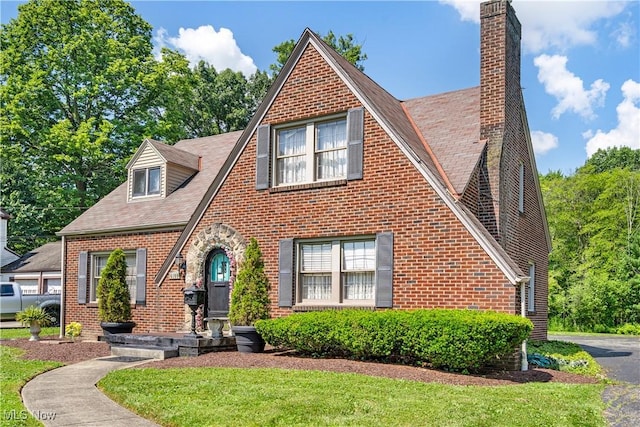 6100 Glenwood Ave, Boardman, OH 44512 - tudor home with brick siding, a chimney, a front lawn, and a shingled roof