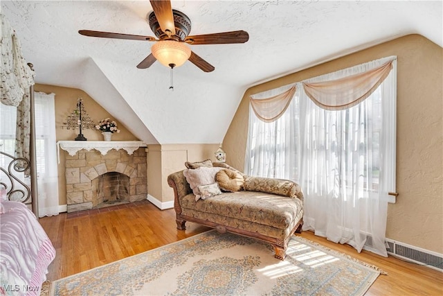 6100 Glenwood Ave, Boardman, OH 44512 - living area with vaulted ceiling, wood finished floors, ceiling fan, a textured ceiling, and a stone fireplace
