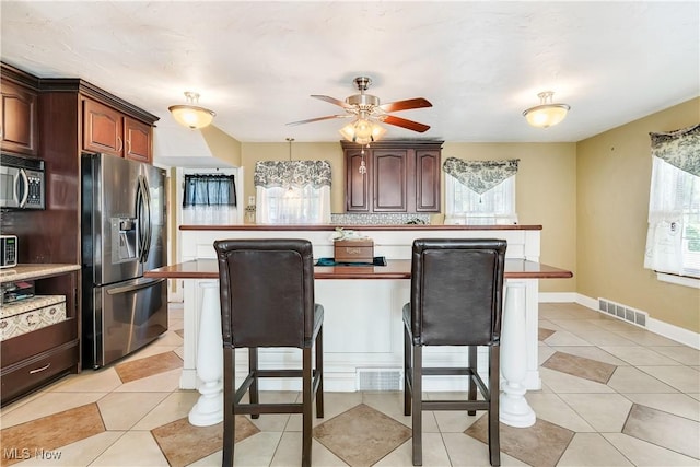 6100 Glenwood Ave, Boardman, OH 44512 - kitchen with stainless steel appliances, a breakfast bar area, a ceiling fan, and light tile patterned floors