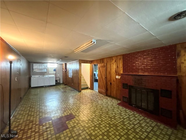 3109 Latimer Ave, Ashtabula, OH 44004 - unfurnished living room with wooden walls, a brick fireplace, stairway, and tile patterned floors