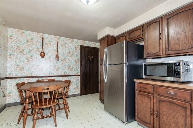 751 Bacon Rd, Oh, OH 44077 - kitchen featuring stainless steel appliances, light floors, wallpapered walls, and brown cabinets