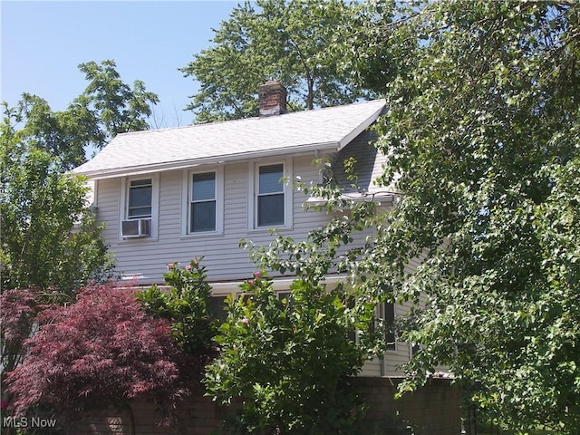 24 E 220th St E, Euclid, OH 44123 - view of side of property featuring a chimney, a shingled roof, and cooling unit