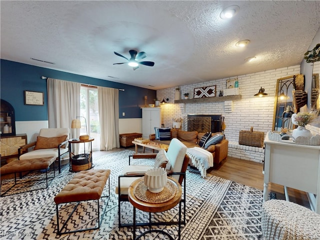 14003 Highview Dr, Dalton, OH 44618 - living area featuring a textured ceiling, a ceiling fan, brick wall, a fireplace, and a wainscoted wall