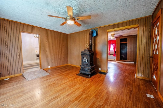 55225 Township Road 224, Fresno, OH 43824 - spare room featuring ceiling fan, a wood stove, wood finished floors, heating unit, and wood walls