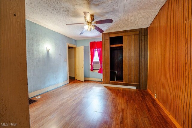 55225 Township Road 224, Fresno, OH 43824 - unfurnished bedroom featuring wood finished floors, wood walls, and a ceiling fan