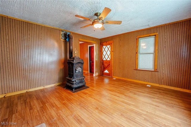 55225 Township Road 224, Fresno, OH 43824 - unfurnished living room featuring a wood stove, ceiling fan, wood finished floors, and wood walls