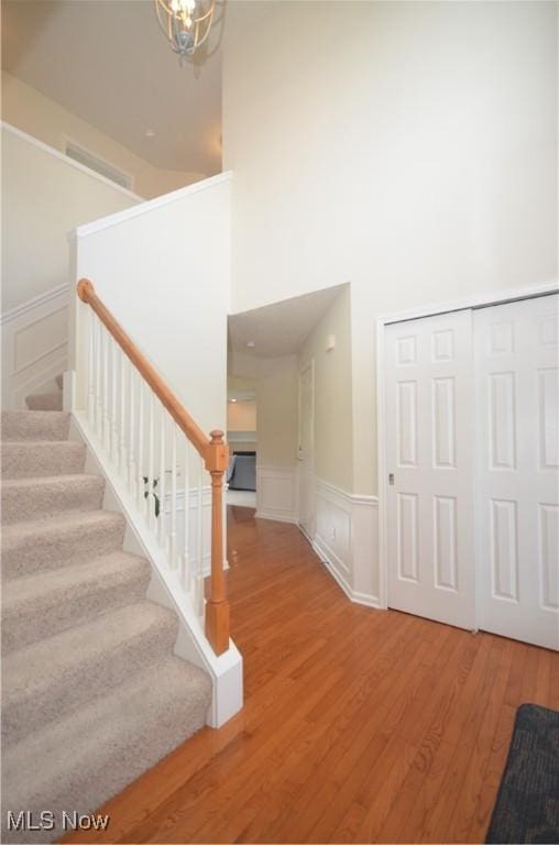 4909 Garnet Cir, Stow, OH 44224 - staircase with a decorative wall, wood finished floors, a towering ceiling, wainscoting, and a chandelier