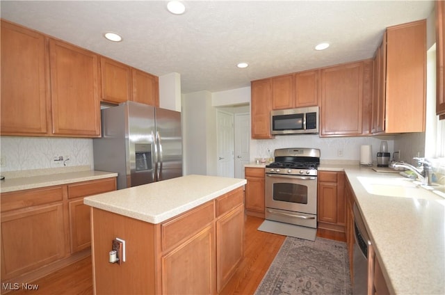4909 Garnet Cir, Stow, OH 44224 - kitchen with appliances with stainless steel finishes, light wood-style floors, a center island, tasteful backsplash, and light countertops