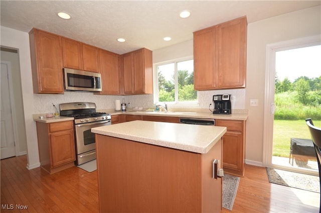 4909 Garnet Cir, Stow, OH 44224 - kitchen with appliances with stainless steel finishes, light wood-style floors, light countertops, backsplash, and a center island