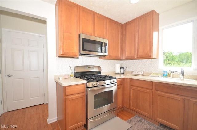 4909 Garnet Cir, Stow, OH 44224 - kitchen featuring stainless steel appliances, light wood-style flooring, light countertops, and tasteful backsplash
