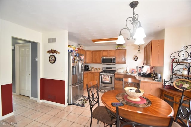 307 Crimson Cir, Campbell, OH 44405 - kitchen featuring appliances with stainless steel finishes, light tile patterned floors, light countertops, and hanging light fixtures