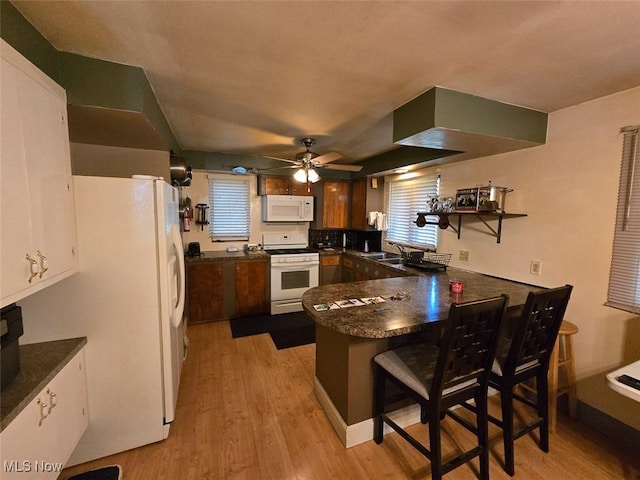 4544 Springvale Ave SW, Canton, OH 44706 - kitchen featuring white appliances, a peninsula, dark countertops, light wood-style floors, and ceiling fan