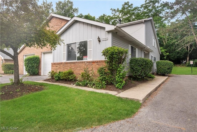1226 Ramblewood Trl, South Euclid, OH 44121 - view of front of home with driveway, brick siding, board and batten siding, a front yard, and an attached garage