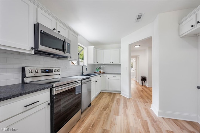 1226 Ramblewood Trl, South Euclid, OH 44121 - kitchen featuring stainless steel appliances, light wood finished floors, white cabinetry, and decorative backsplash