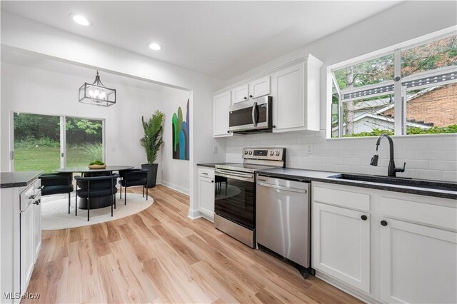 1226 Ramblewood Trl, South Euclid, OH 44121 - kitchen with appliances with stainless steel finishes, decorative backsplash, white cabinetry, a chandelier, and pendant lighting