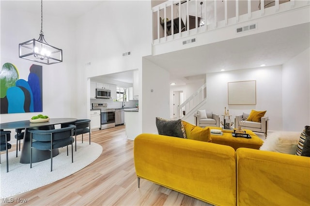 1226 Ramblewood Trl, South Euclid, OH 44121 - living area featuring light wood finished floors, a chandelier, a towering ceiling, and stairway