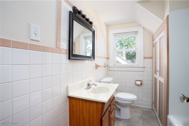 289 E Baird Ave, Barberton, OH 44203 - full bathroom featuring tile walls, vanity, lofted ceiling, a wainscoted wall, and a bath