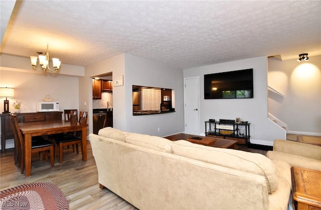 4914 Independence Cir Unit D, Stow, OH 44224 - living area featuring light wood-style flooring, a chandelier, stairs, and a textured ceiling