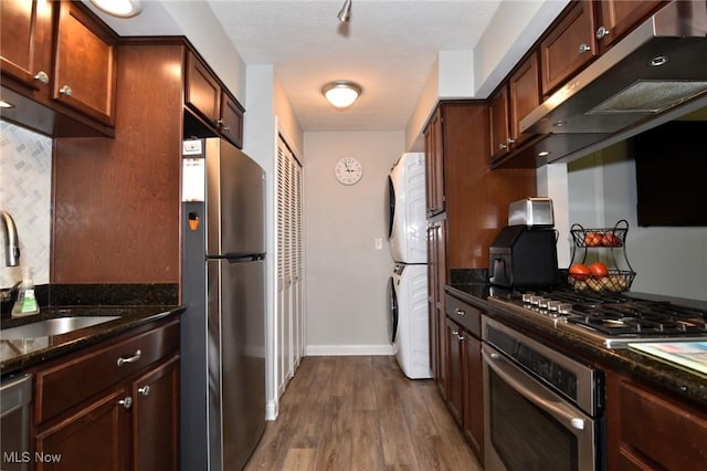 4914 Independence Cir Unit D, Stow, OH 44224 - kitchen with stainless steel appliances, estacked washer and dryer, dark wood finished floors, dark stone countertops, and range hood
