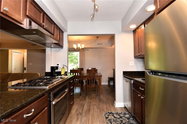 4914 Independence Cir Unit D, Stow, OH 44224 - kitchen featuring stainless steel appliances, wood finished floors, under cabinet range hood, a chandelier, and dark stone counters