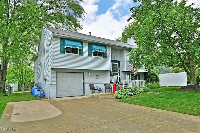 2555 Walnut St, Girard, OH 44420 - split foyer home featuring a garage, a chimney, and concrete driveway
