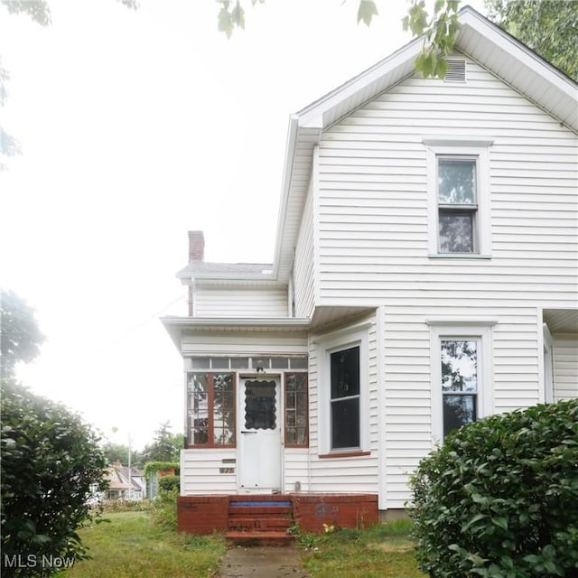 625 W Church St, Orrville, OH 44667 - view of front of property featuring a sunroom, entry steps, and a chimney