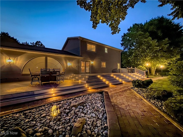 12147 Gladstone Rd SW, North Jackson, OH 44451 - back of house at night featuring a wooden deck and outdoor dining area
