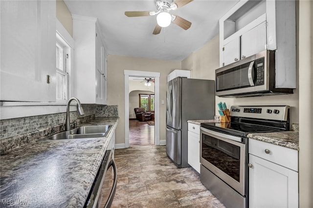 1425 Keefer Rd, Girard, OH 44420 - kitchen featuring stainless steel appliances, a ceiling fan, tasteful backsplash, white cabinets, and arched walkways
